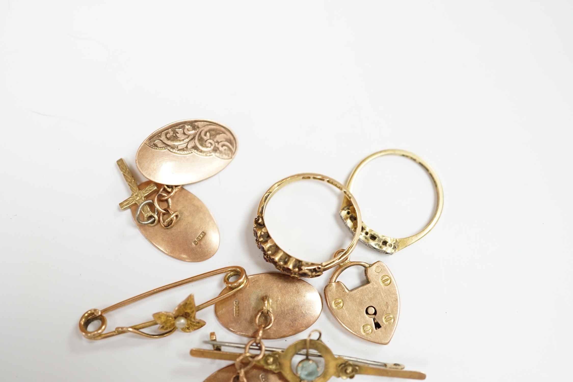 A pair of engraved 9ct gold oval cufflinks, two yellow metal bar brooches including 9ct, a 15ct gold and gem set ring (lacking stones), an 18ct and five stone diamond chip set ring and two 9ct charms. Condition - poor to